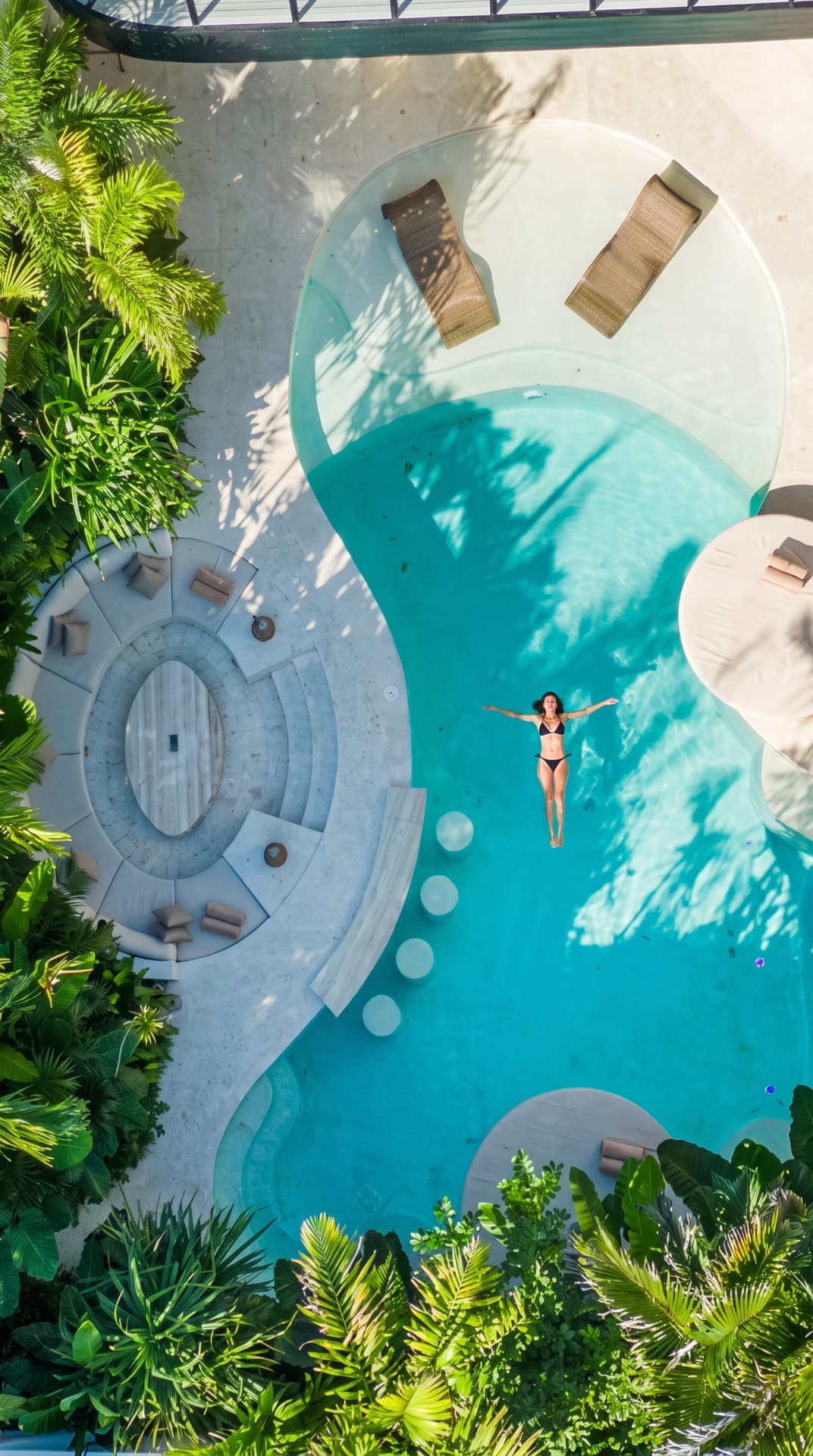 Model floating in the curved villa pool, aerial view