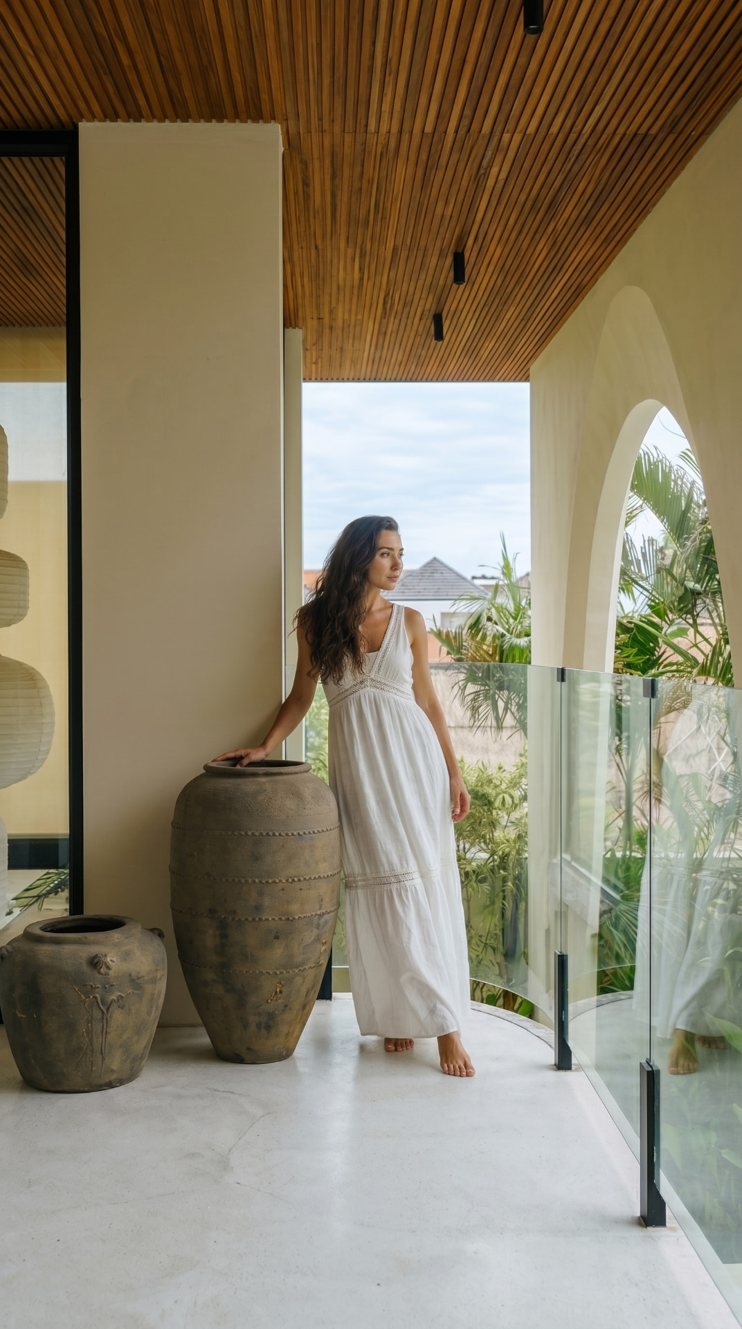 Model in a white dress on the villa balcony beside terracotta urns